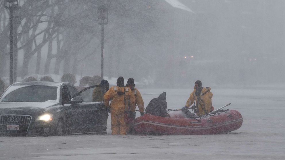 Firefighters wearing ice rescue suits help a stranded motorist, in Boston, Mass., Jan. 4, 2018. 