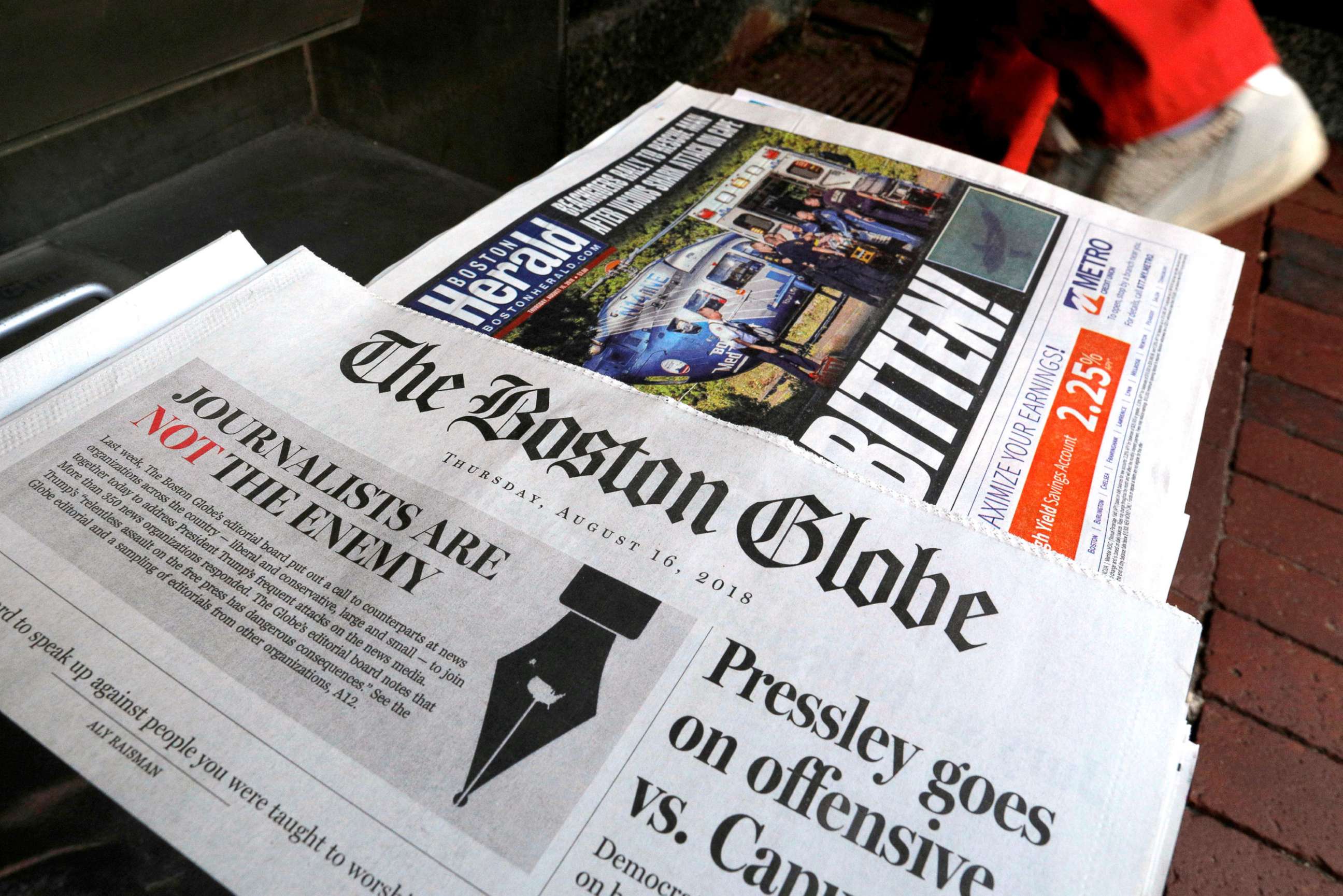 PHOTO: A customer walks past the front page of the Boston Globe newspaper referencing their editorial defense of press freedom at a newsstand in Cambridge, Aug. 16, 2018. 