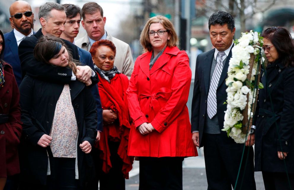 The family of Lu, Jun Lu observe a moment of silence with the family of Martin Richard, foreground during a ceremony at the site where Martin Richard and Lingzi Lu were killed in the second explosion at the 2013 Boston Marathon, April 15, 2018, in Boston.