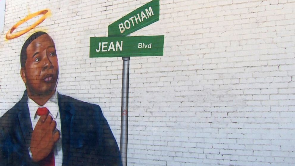 PHOTO: A mural depicts the late Botham Jean and a street sign with his name on it, March 26, 2021, in Dallas.