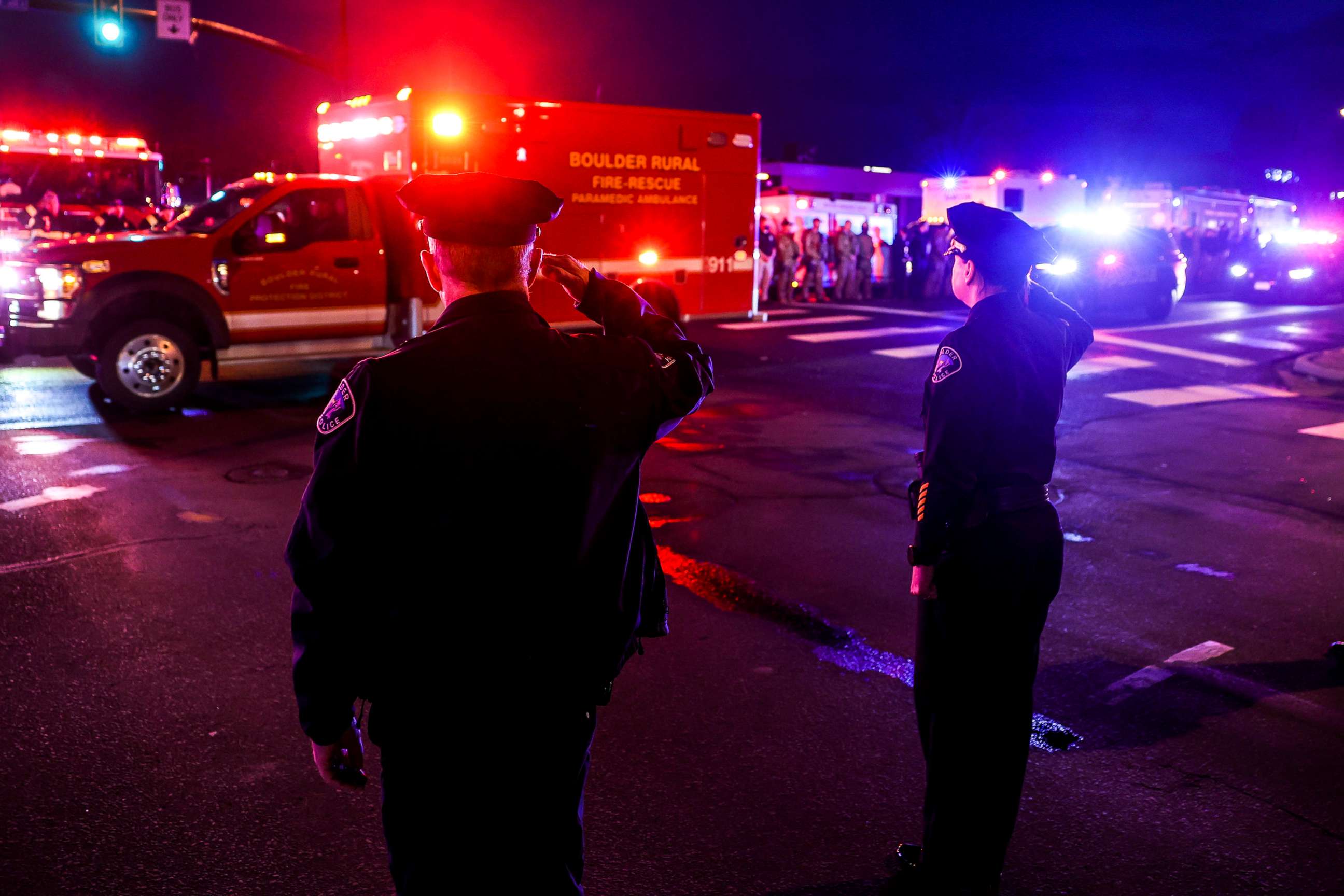 PHOTO: Police officers salute as emergency vehicles escort the body of slain a police officer from the scene of a shooting at a King Soopers grocery store in Boulder Colo. on March 22. 2021.