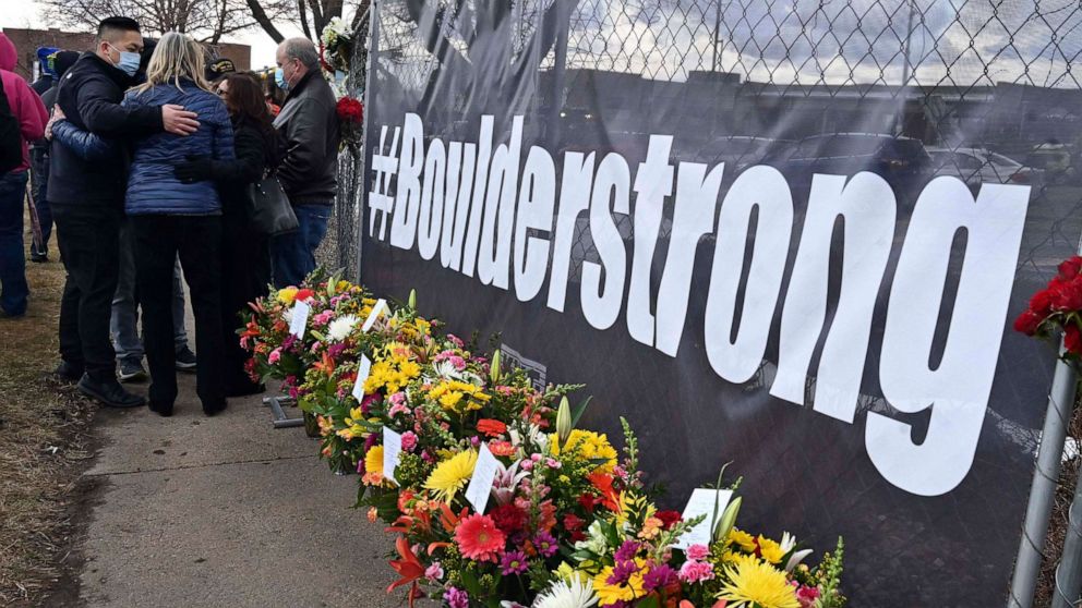 PHOTO: A solemn group of King Soopers employees, left, some from the Boulder store and some from the same district, gather after placing flowers for each of the victims of a mass shooting at a Boulder Kings Soopers store, March 23, 2021.
