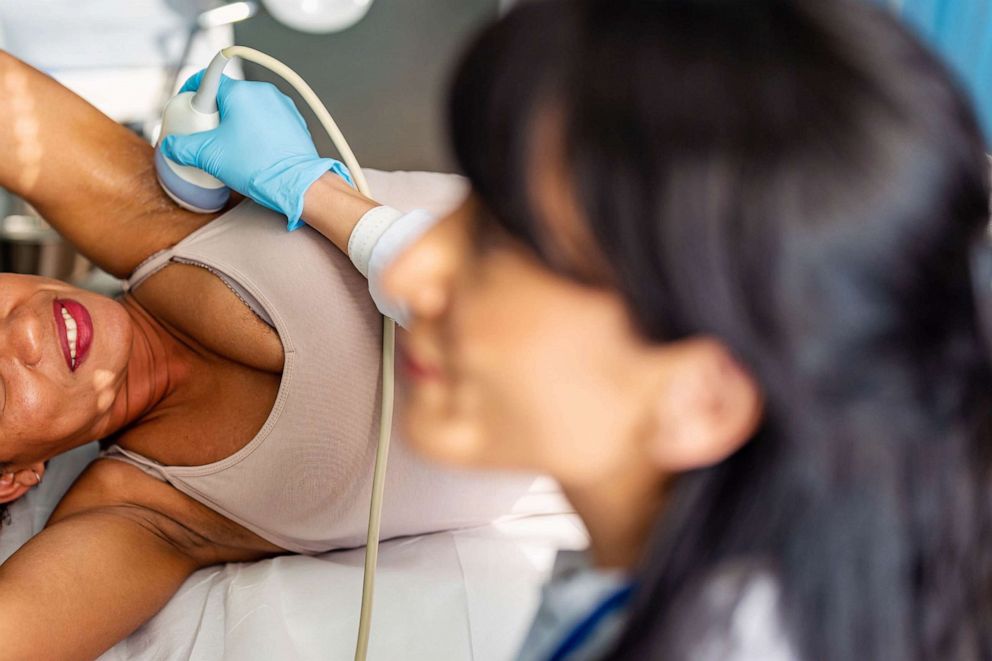 STOCK PHOTO: A doctor performs ultrasound examination of breast of a patient in a clinic