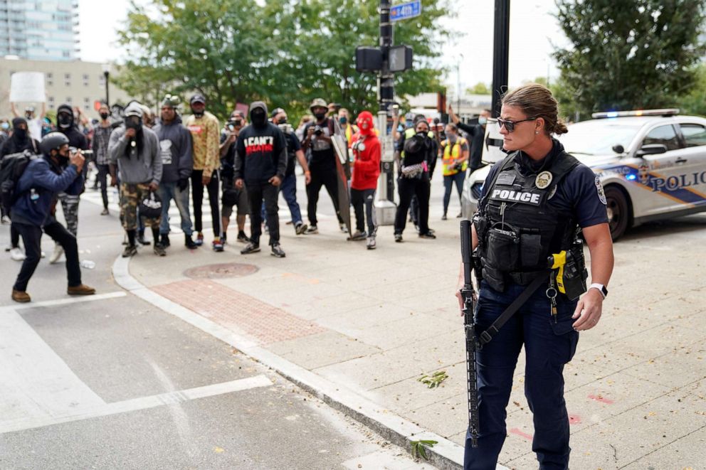 PHOTO: A police officer looks on as people react after a decision in the criminal case against police officers involved in the death of Breonna Taylor, who was shot dead by police in her apartment, in Louisville, Ky., Sept. 23, 2020.