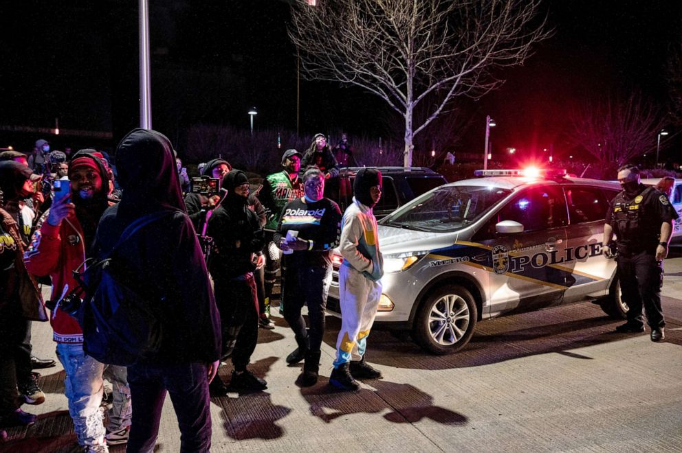 PHOTO: A group of protesters are illuminated by emergency lights from Louisville Metro Police Department vehicles after the Breonna Taylor memorial events, March 13, 2021, in Louisville, Kentucky.