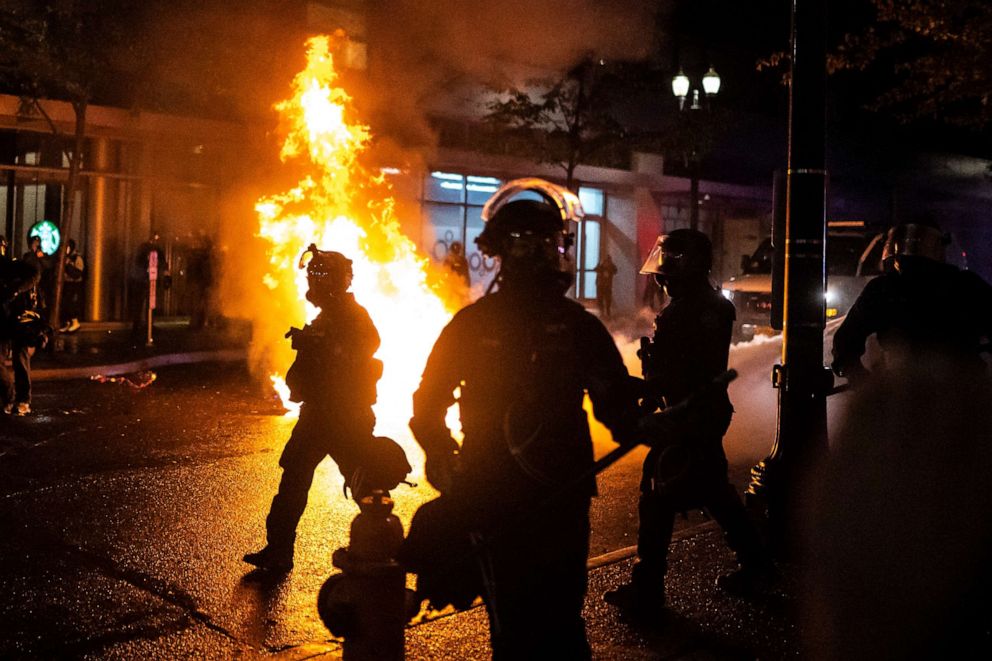 PHOTO: Portland police walk past a fire started by a Molotov cocktail thrown at police, Sept. 23, 2020, in Portland, Oregon.