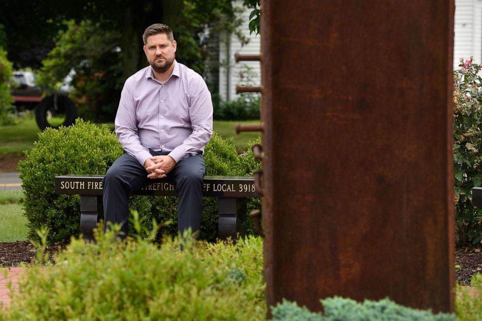 PHOTO: Brett Eagleson, son of Sept. 11 victim Bruce Eagleson, sits in a memorial garden with a beam from the World Trade Center, July 2, 2021, at South Fire District in Middletown, Conn.