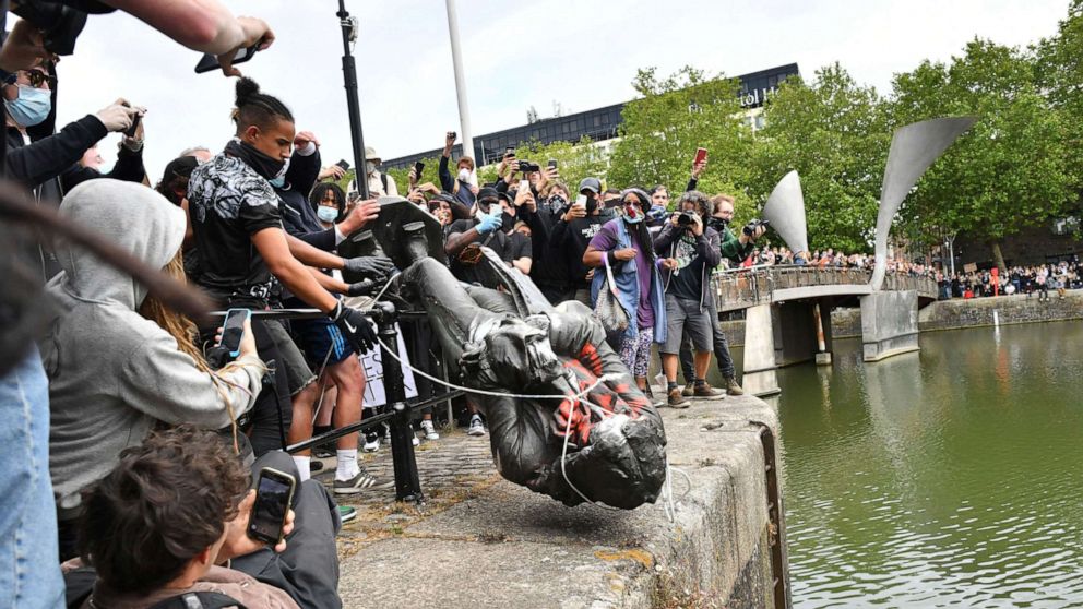 PHOTO: Protesters throw a statue of slave trader Edward Colston into Bristol harbour, during a Black Lives Matter protest rally, in Bristol, England, June 7, 2020, in response to the recent death of George Floyd. 