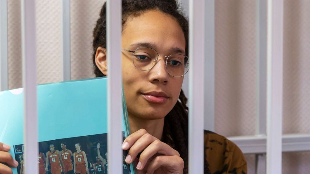 PHOTO: WNBA star and two-time Olympic gold medalist Brittney Griner holds up a photo of players from the recent all star game wearing her number, sitting in a cage at a court room prior to a hearing in the Khimki district court, July 15, 2022.