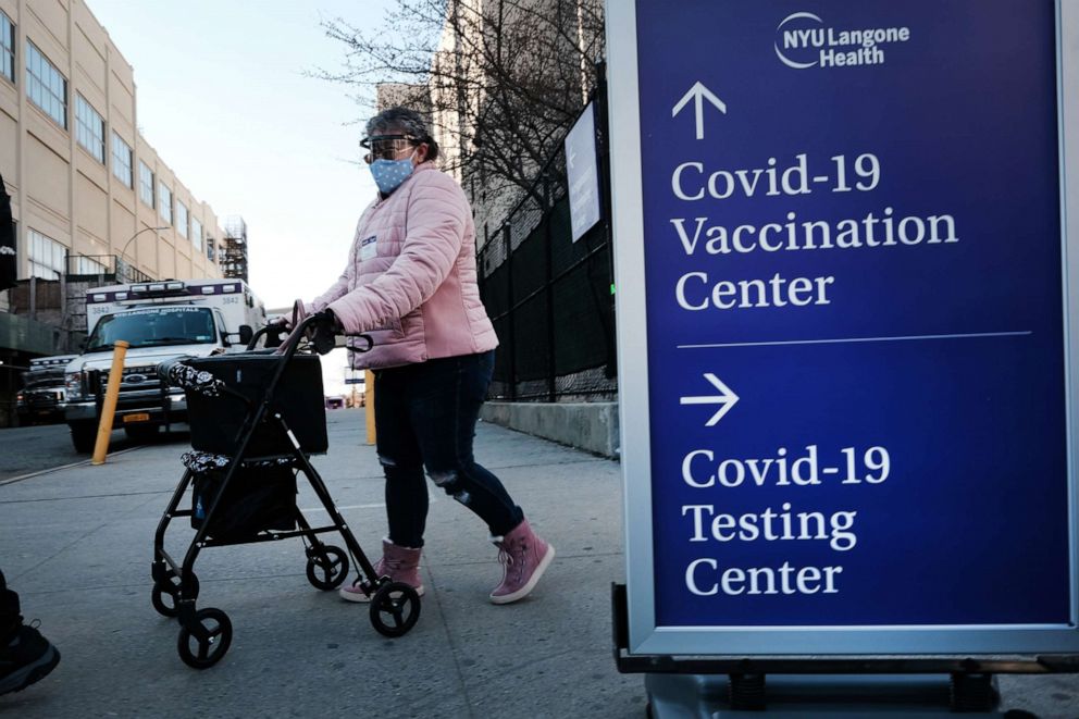 PHOTO: People walk by a sign for both a Covid-19 testing clinic and a Covid vaccination location outside of a Brooklyn hospital, March, 29 2021, in New York City.