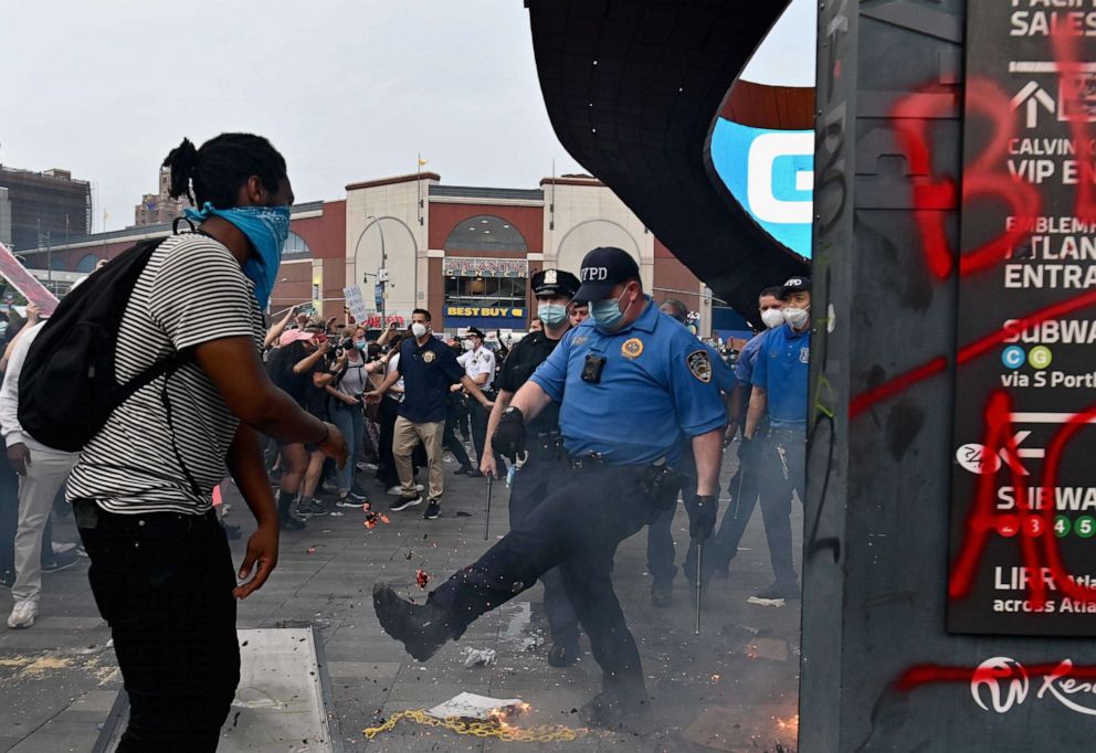 PHOTO: A police officer gestures near a small fire burning as protesters gather for a "Black Lives Matter" protest near Barclays Center on May 29, 2020 in Brooklyn, New York, after George Floyd died while being arrested by a police officer in Minneapolis.