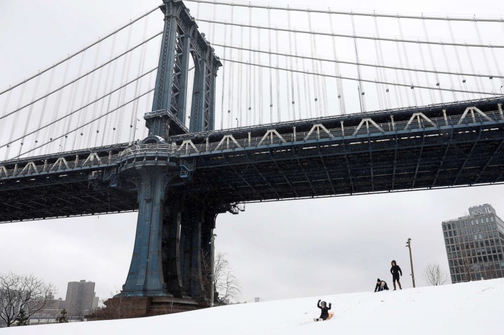 PHOTO: A child raises his hands while sledding during snowfall at Brooklyn Bridge Park in New York, April 2, 2018.