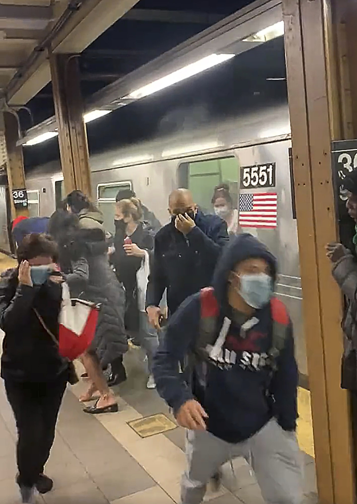 PHOTO: In this photo from social media video, passengers run from a subway car in a station in the Brooklyn borough of New York, April 12, 2022.
