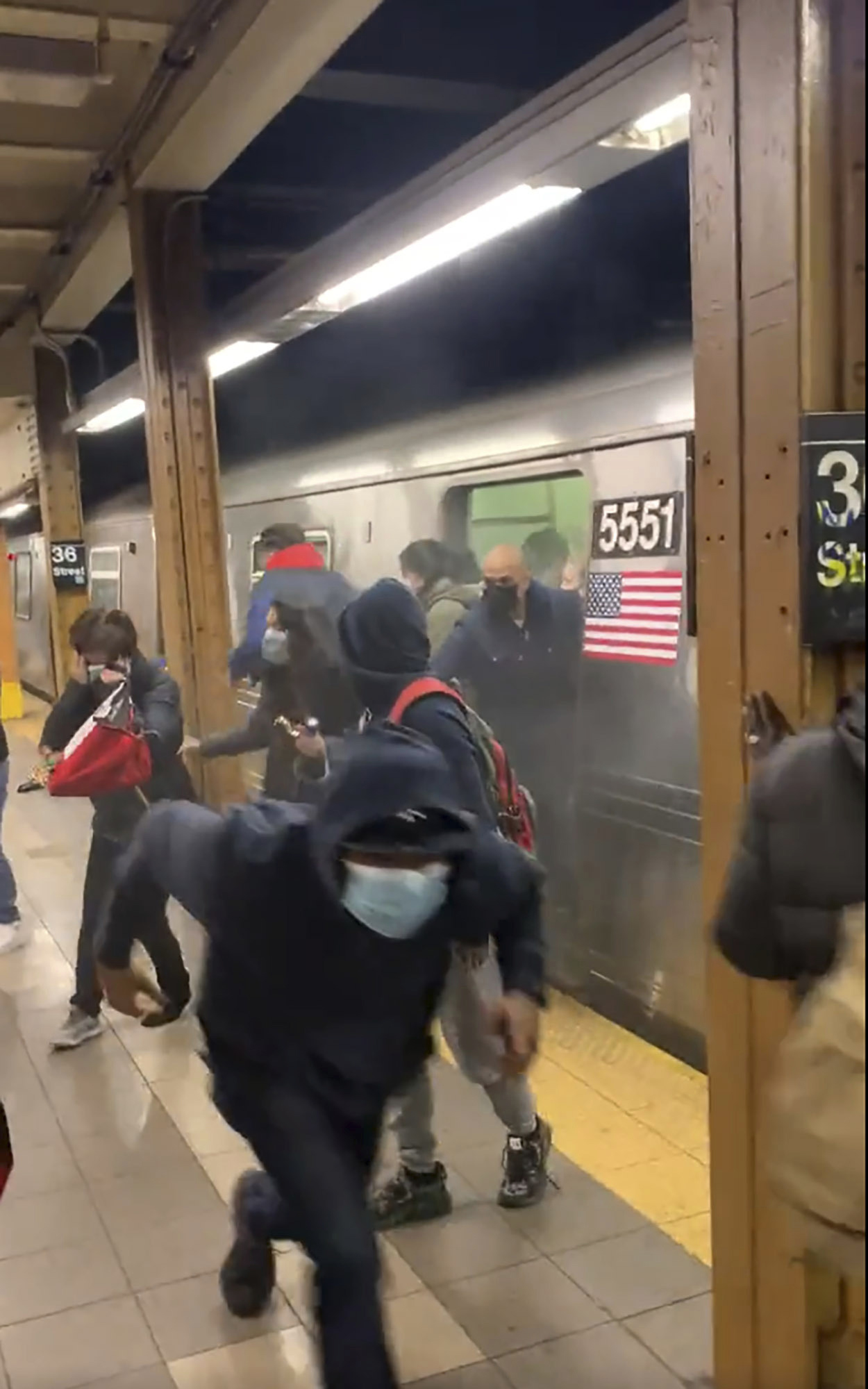 PHOTO: In this photo from social media video, passengers run from a subway car in a station in the Brooklyn borough of New York, April 12, 2022. 