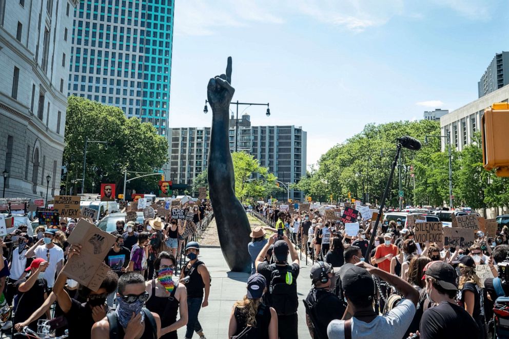 PHOTO: Thousands of protesters hoding signs walk past Brooklyn's finger sculpture in Brooklyn, New York, June 19, 2020.