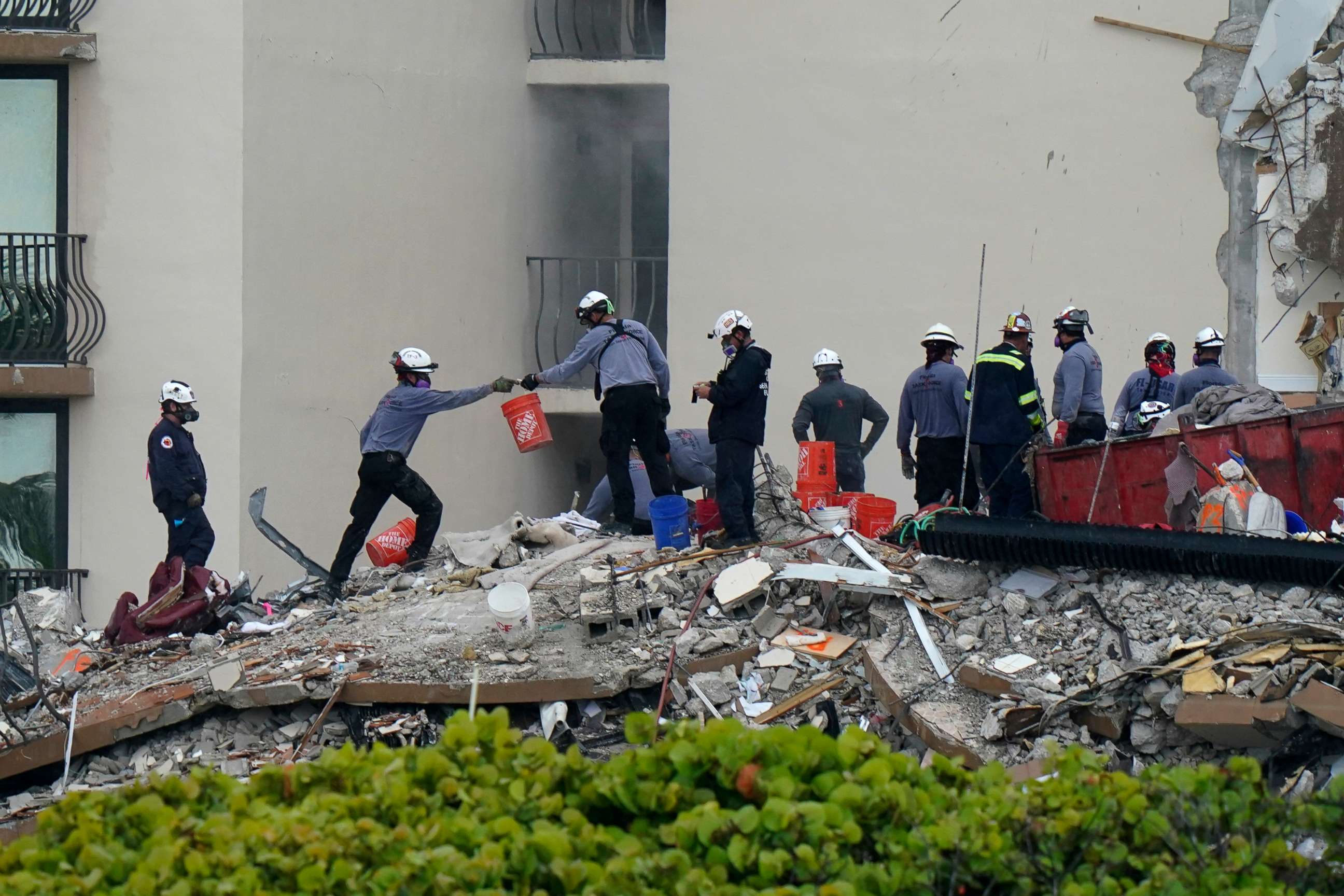 PHOTO: Search and rescue personnel pass buckets as they work atop the rubble at the Champlain Towers South condo building, where scores of people remain missing almost a week after it partially collapsed, June 30, 2021, in Surfside, Fla.