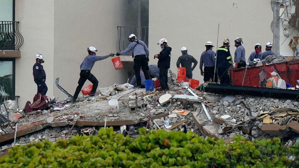 PHOTO: Search and rescue personnel pass buckets as they work atop the rubble at the Champlain Towers South condo building, where scores of people remain missing almost a week after it partially collapsed, June 30, 2021, in Surfside, Fla.