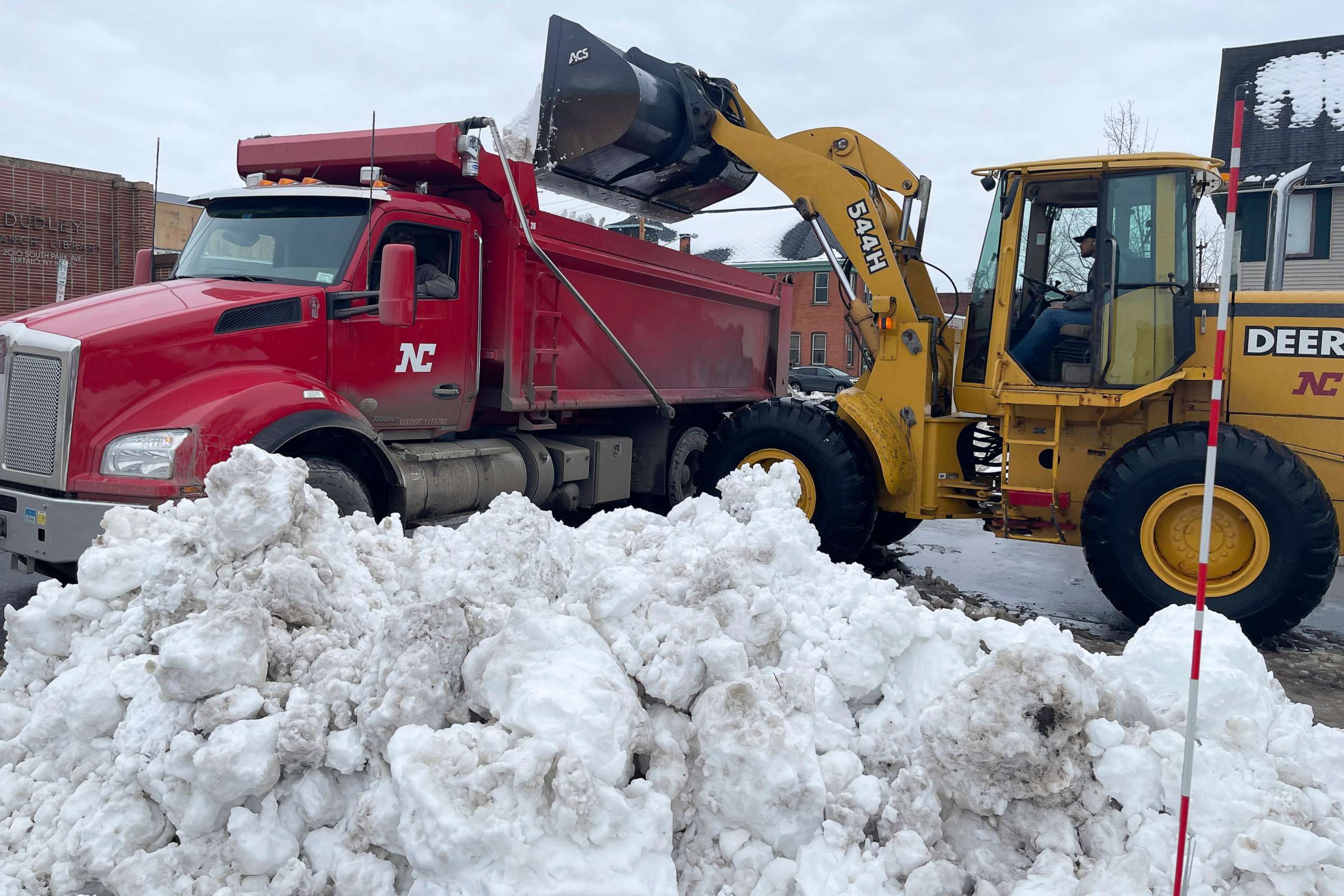 PHOTO: A front loader dumps snow into a dump truck along a residential street in Buffalo, New York, Dec. 29, 2022.