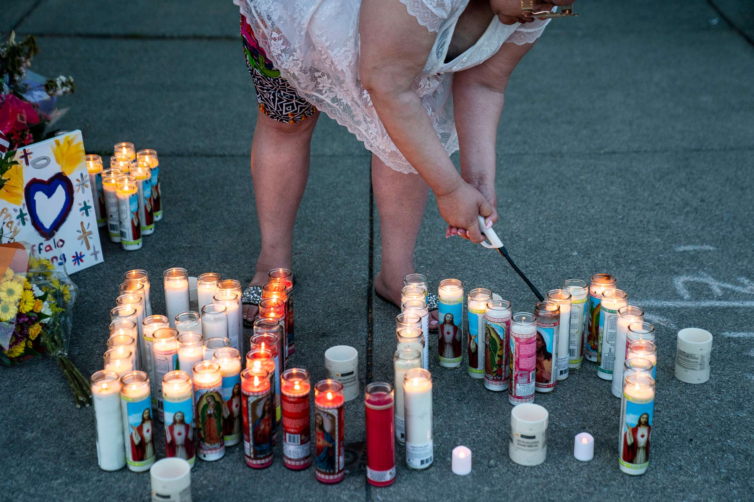 PHOTO: Sherri Singletary, of Buffalo, lights candles that spell BLM as people gather at the scene of a mass shooting at Tops Friendly Market at Jefferson Avenue and Riley Street on May 15, 2022, in Buffalo, NY.