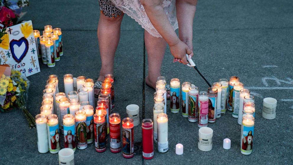 PHOTO: Sherri Singletary, of Buffalo, lights candles that spell BLM as people gather at the scene of a mass shooting at Tops Friendly Market at Jefferson Avenue and Riley Street on May 15, 2022, in Buffalo, NY.