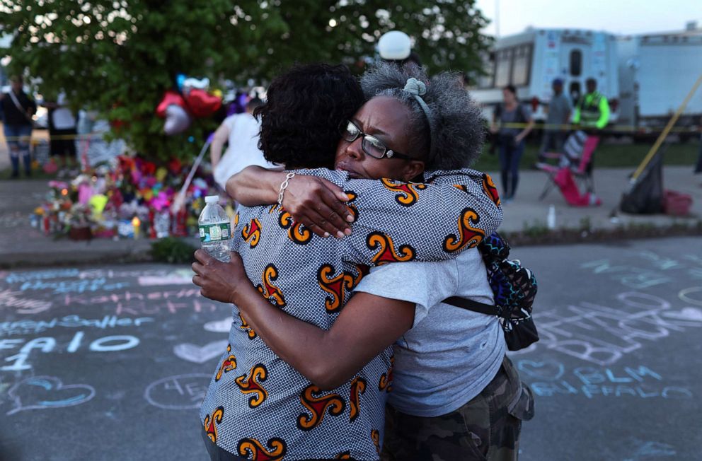 PHOTO: Mourners hugr while visiting a makeshift memorial outside of Tops supermarket on May 15, 2022 in Buffalo, New York after a mass shooting.