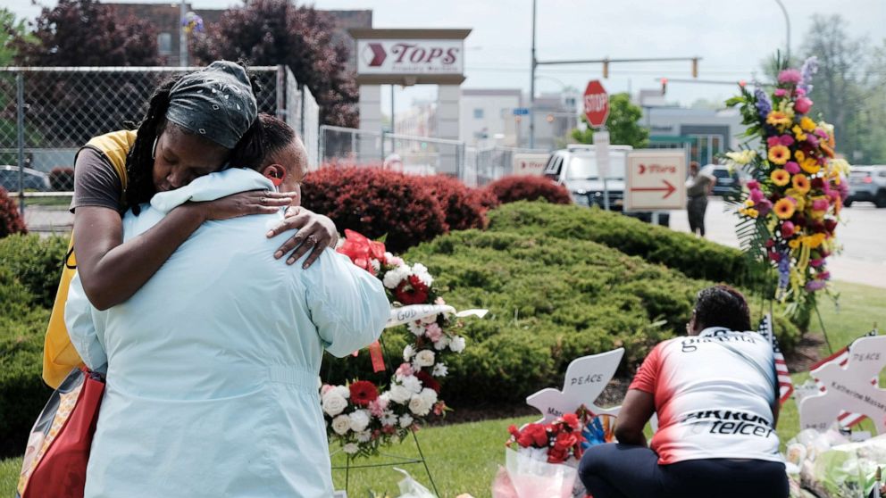 PHOTO: People embrace near a memorial for the shooting victims outside of Tops grocery store, May 20, 2022, in Buffalo, NY, where 10 people died during a mass shooting on May 14.