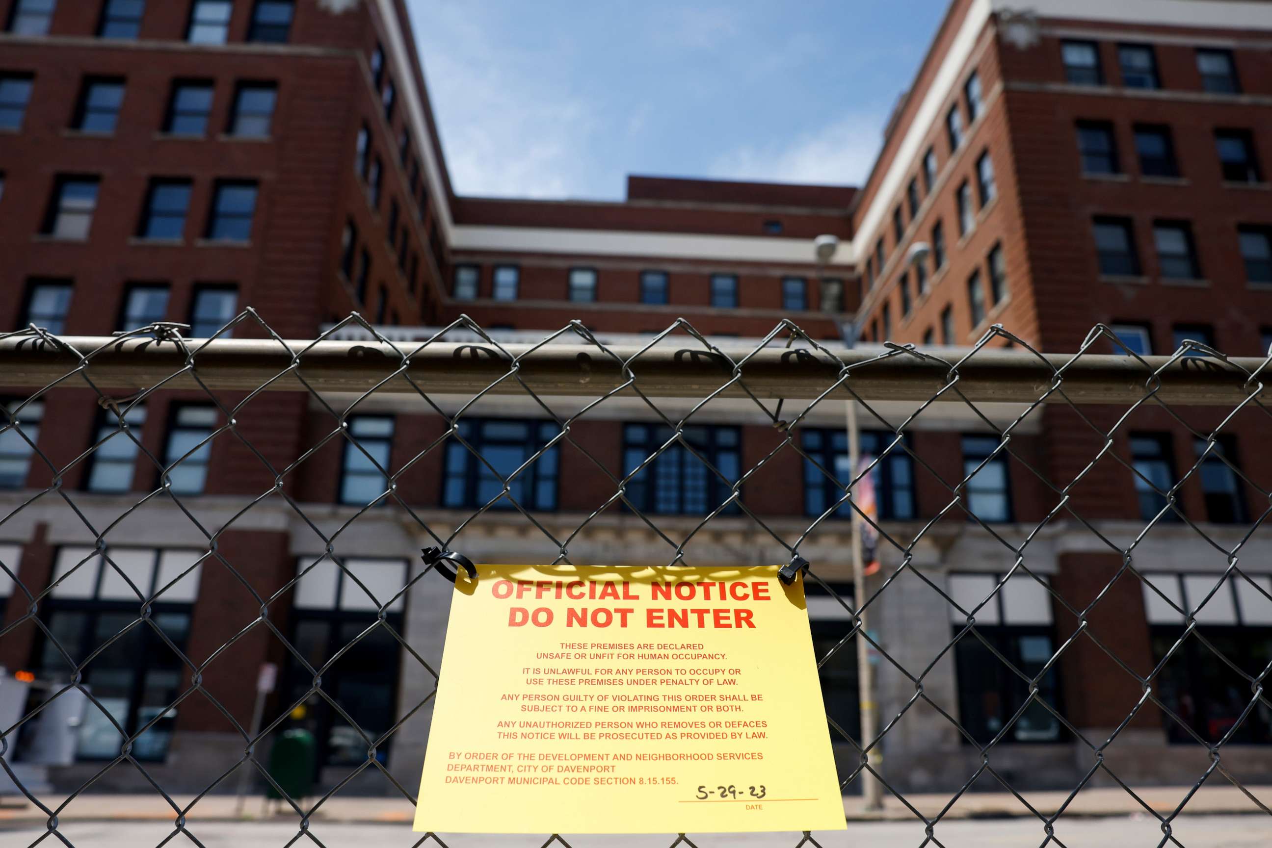 PHOTO: A yellow "official notice do not enter" sign hangs on a fence around The Davenport, 324 Main Street, in Davenport, Iowa, on May 29, 2023, after a section of the building collapsed.