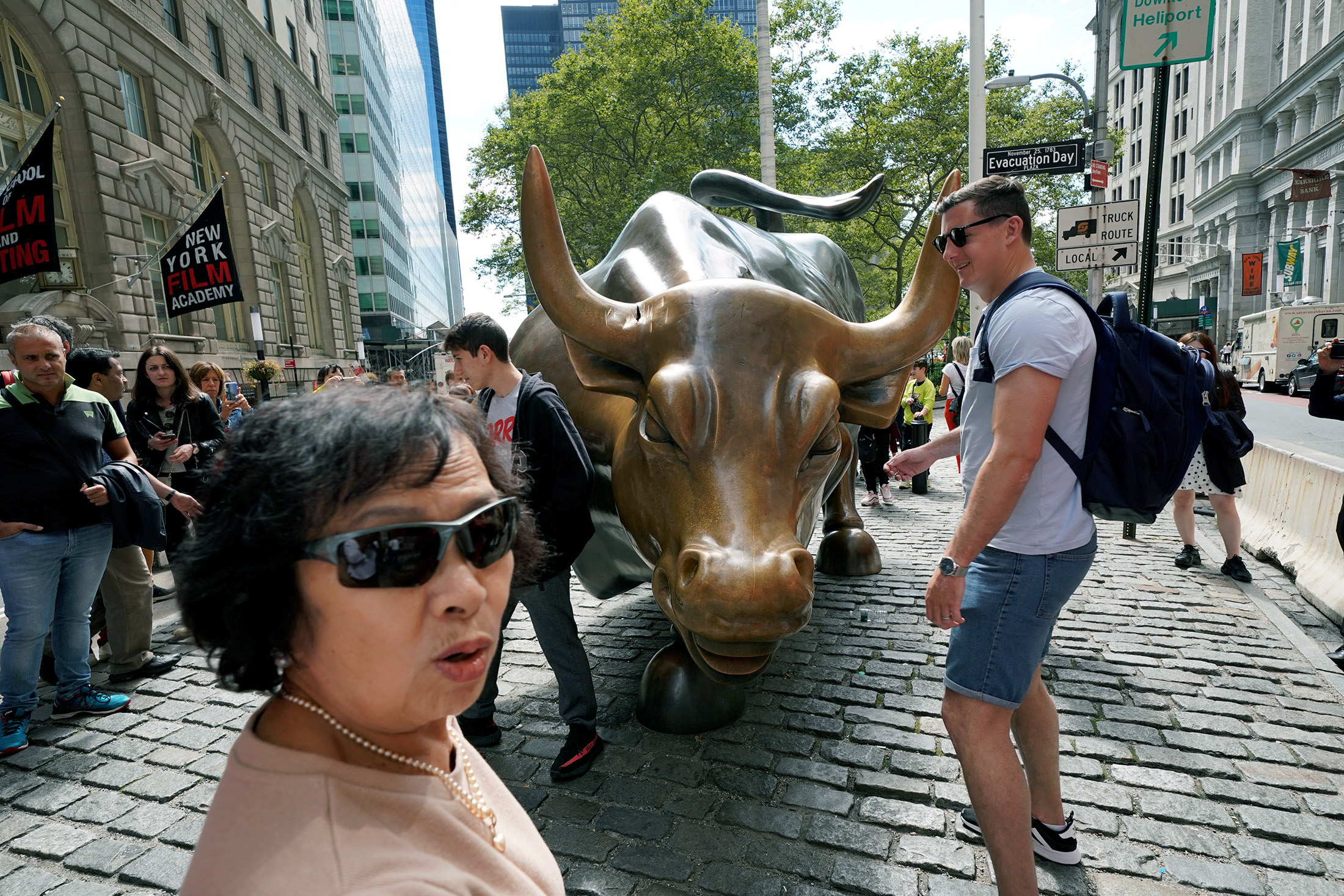 PHOTO: Pedestrians view the damage, visible near the base of one of its horns, to the iconic bronze Charging Bull statue on Wall Street in New York, Sept. 8, 2019.