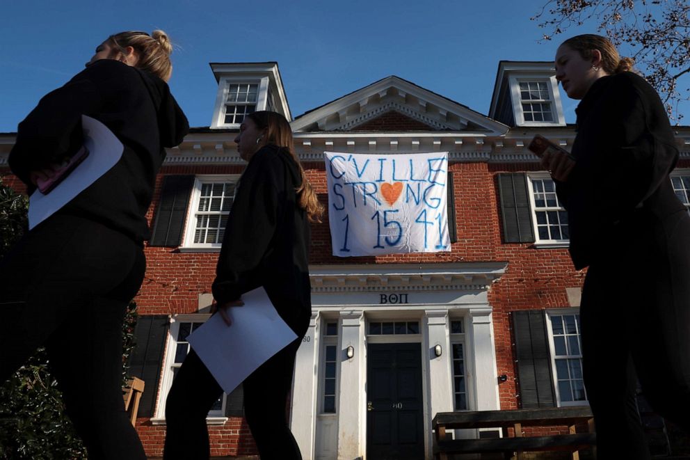 PHOTO: Students walk past a fraternity house with a banner memorializing three University of Virginia football players killed during an overnight shooting at the university, Nov. 14, 2022, in Charlottesville, Va.