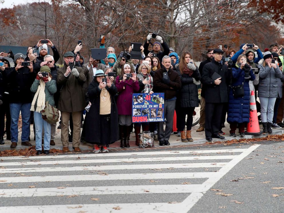 PHOTO: People line the street as the hearse carrying the flag-draped casket of former President George H.W. Bush heads to a State Funeral at the National Cathedral, Dec. 5, 2018, in Washington.