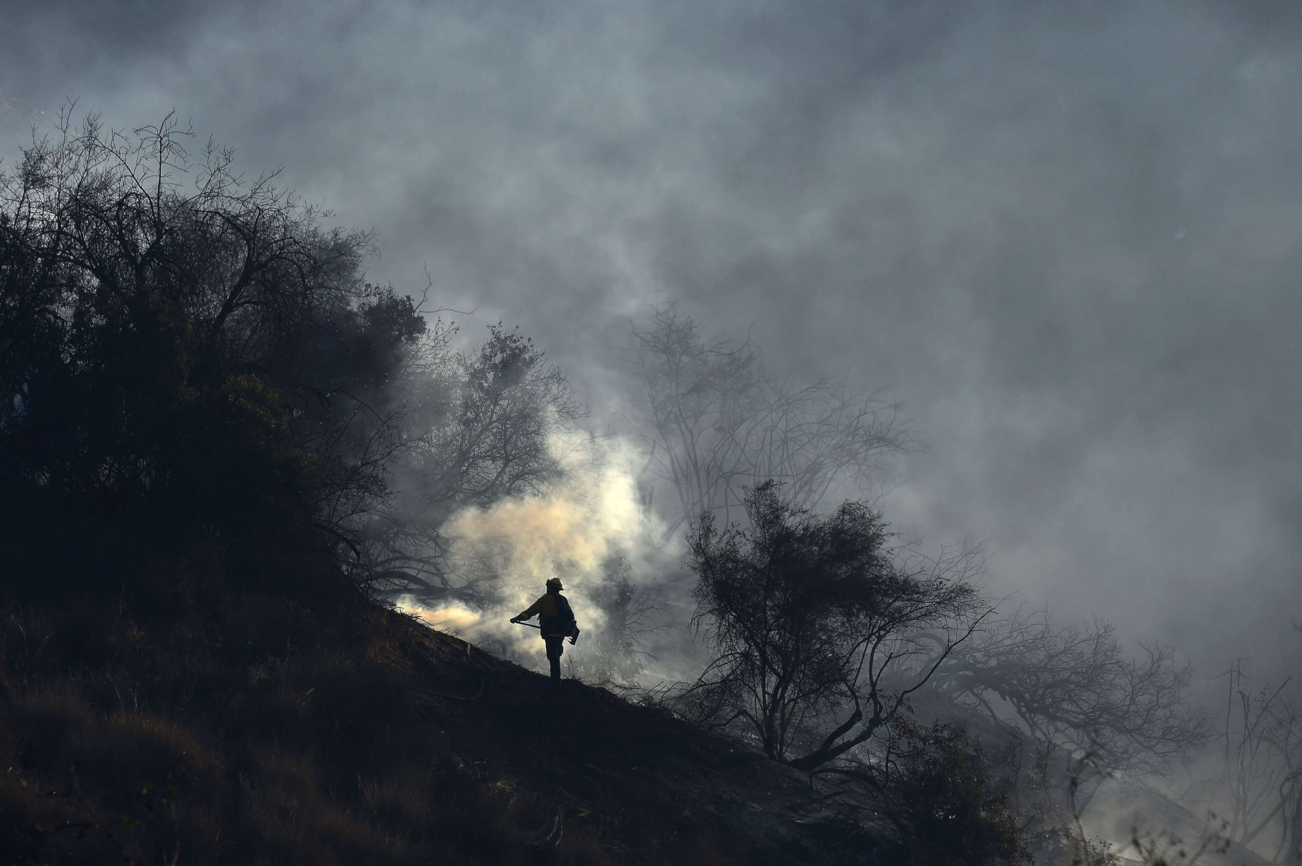 PHOTO: A member of a fire team hand crew monitors embers to prevent fire from jumping to the west side of the 405 freeway, at the Skirball Fire near the Bel Air area of Los Angeles, Dec. 6, 2017.