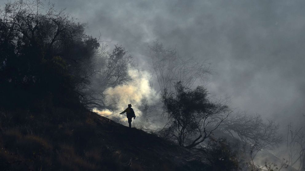 PHOTO: A member of a fire team hand crew monitors embers to prevent fire from jumping to the west side of the 405 freeway, at the Skirball Fire near the Bel Air area of Los Angeles, Dec. 6, 2017.