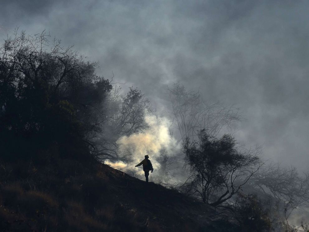 PHOTO: A member of a fire team hand crew monitors embers to prevent fire from jumping to the west side of the 405 freeway, at the Skirball Fire near the Bel Air area of Los Angeles, Dec. 6, 2017.