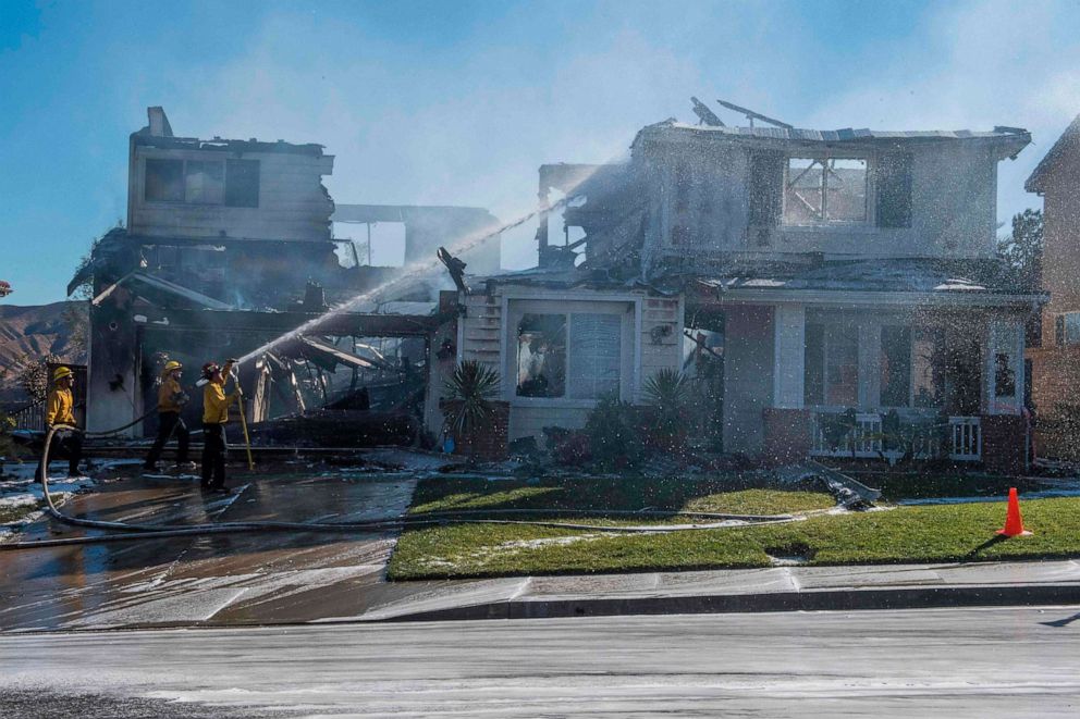 PHOTO: Firefighters hose down a burning house during the Tick Fire in Agua Dulce near Santa Clarita, California on October 25, 2019.