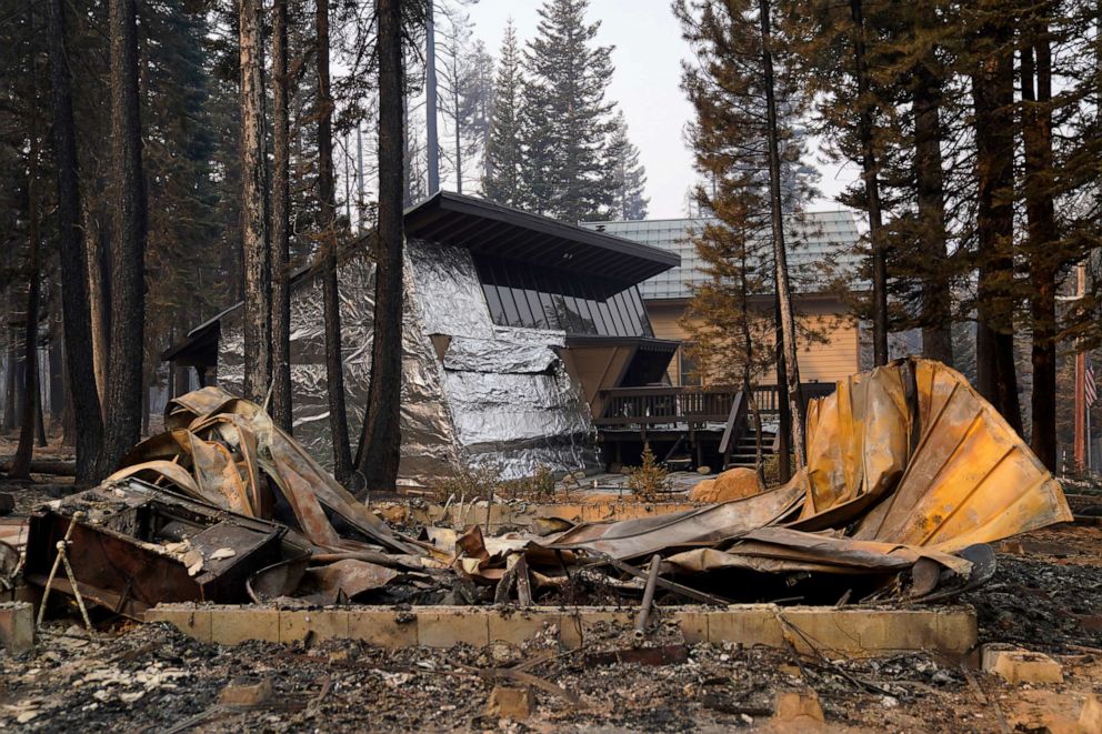 PHOTO: A cabin partially covered in fire-resistant material stands behind a property destroyed in the Caldor Fire in Twin Bridges, Calif., Sept. 2, 2021.