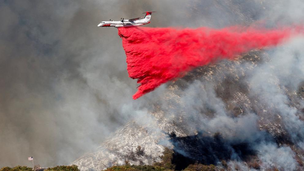 PHOTO: A plane makes a drop as smoke billows from the Palisades Fire at the Mandeville Canyon, in Los Angeles, Calif., Jan. 11, 2025.