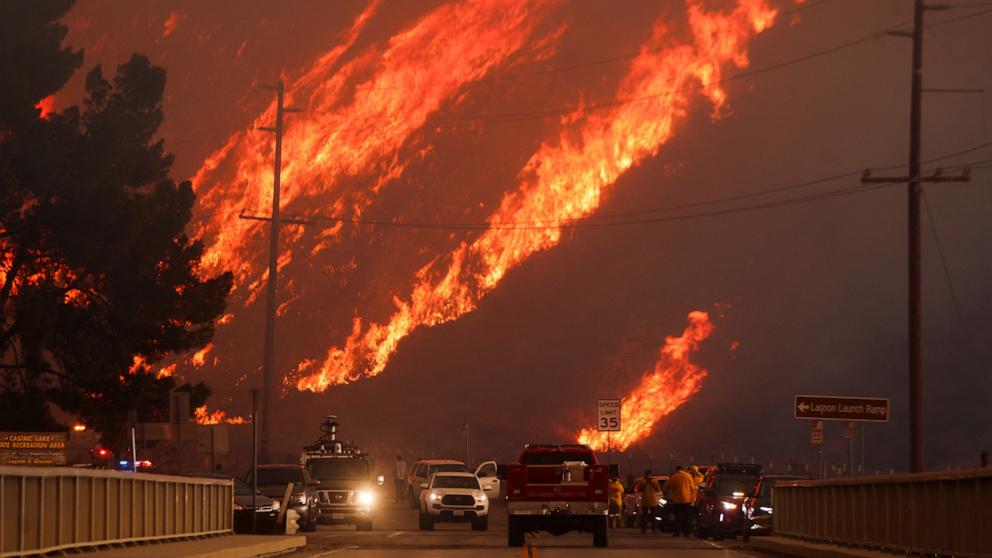 PHOTO: Flames rise behind vehicles as the Hughes Fire burns in Castaic Lake, Calif. Jan. 22, 2025. 