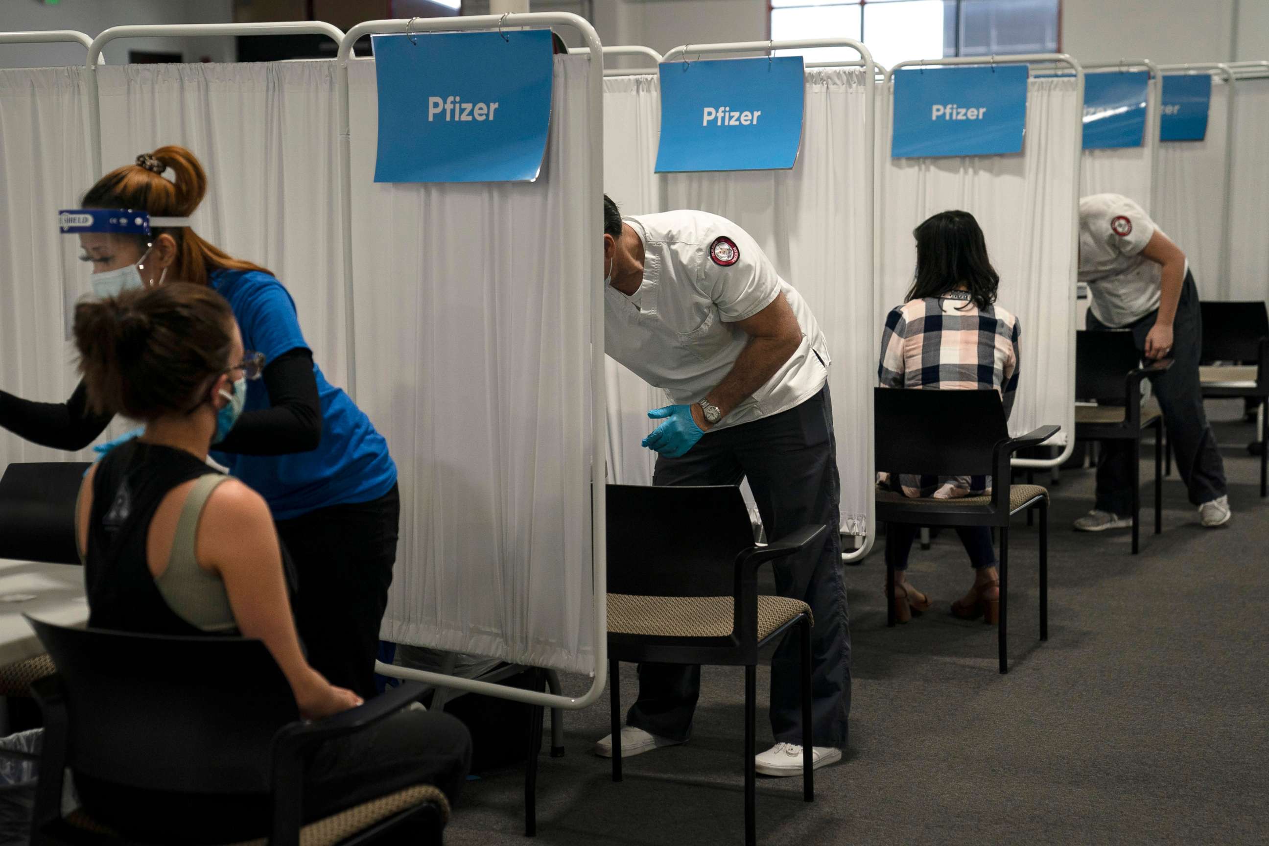 PHOTO: Student nurse Dario Gomez, center, disinfects a chair after administering the Pfizer COVID-19 vaccine to a patient at Providence Edwards Lifesciences vaccination site in Santa Ana, Calif., May 21, 2021.