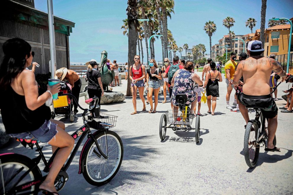 PHOTO: Beachgoers walk and ride along the boardwalk in the Pacific Beach area of San Diego, Calif., July 4, 2020, amid the coronavirus pandemic.