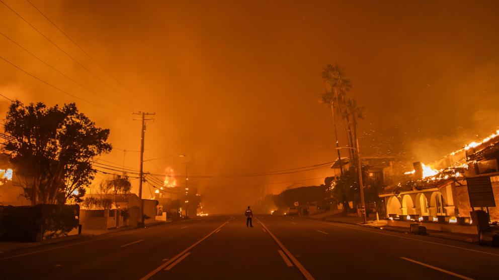 PHOTO: A man watches the flames from the Palisades Fire burning homes on the Pacific Coast Highway amid a powerful windstorm on January 8, 2025 in Los Angeles, Calif.