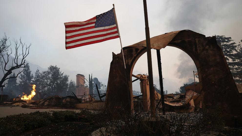 PHOTO: An American flag flies amid burned structures at the Altadena Town & Country Club during the Eaton Fire on Jan. 8, 2025 in Altadena, Calif.