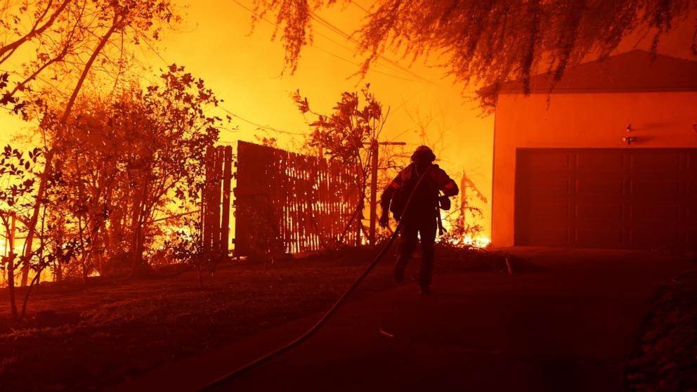 PHOTO: A firefighter pulls a hose up to a home while battling the Eaton Fire on Jan. 8, 2025 in Altadena, Calif.