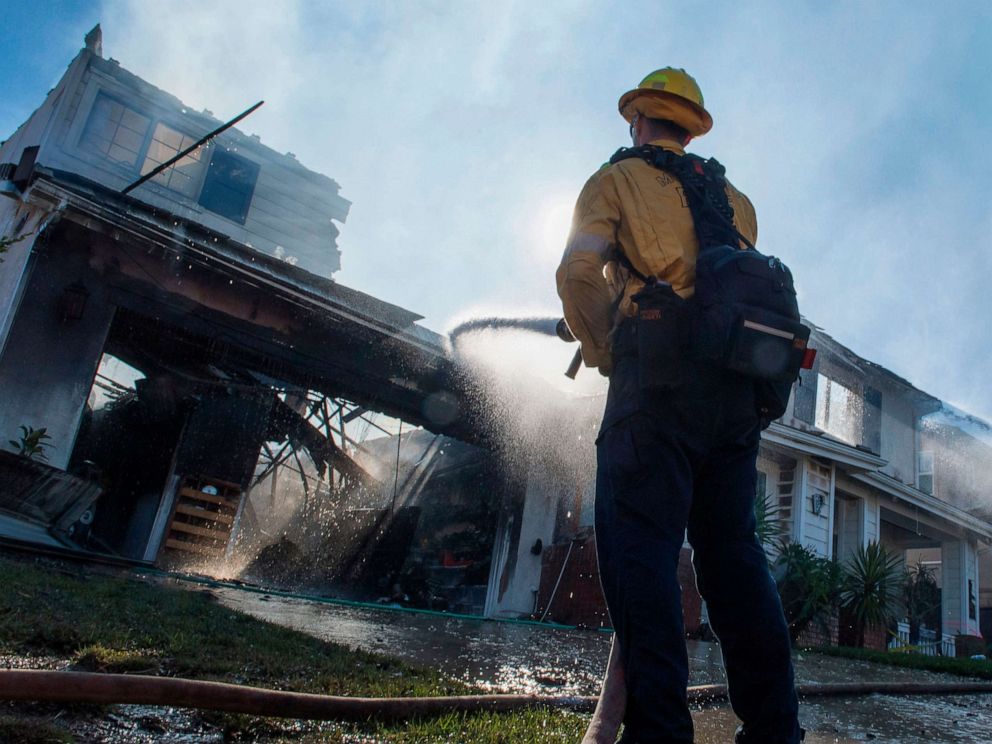 PHOTO: Firefighters hose down a burning house during the Tick Fire in Agua Dulce near Santa Clarita, California on October 25, 2019. 