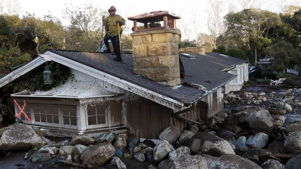PHOTO: A firefighter stands on the roof of a house submerged in mud and rocks, Jan. 10, 2018, in Montecito, Calif.