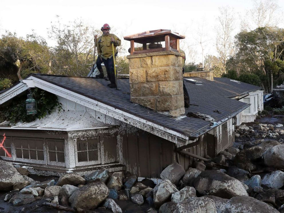 PHOTO: A firefighter stands on the roof of a house submerged in mud and rocks, Jan. 10, 2018, in Montecito, Calif.