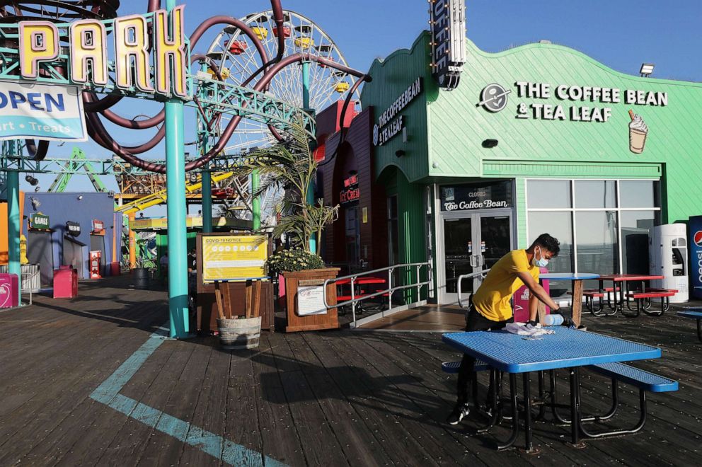 PHOTO: A worker cleans a table on Santa Monica Pier amid the COVID-19 pandemic on July 2, 2020 in Santa Monica, Calif.