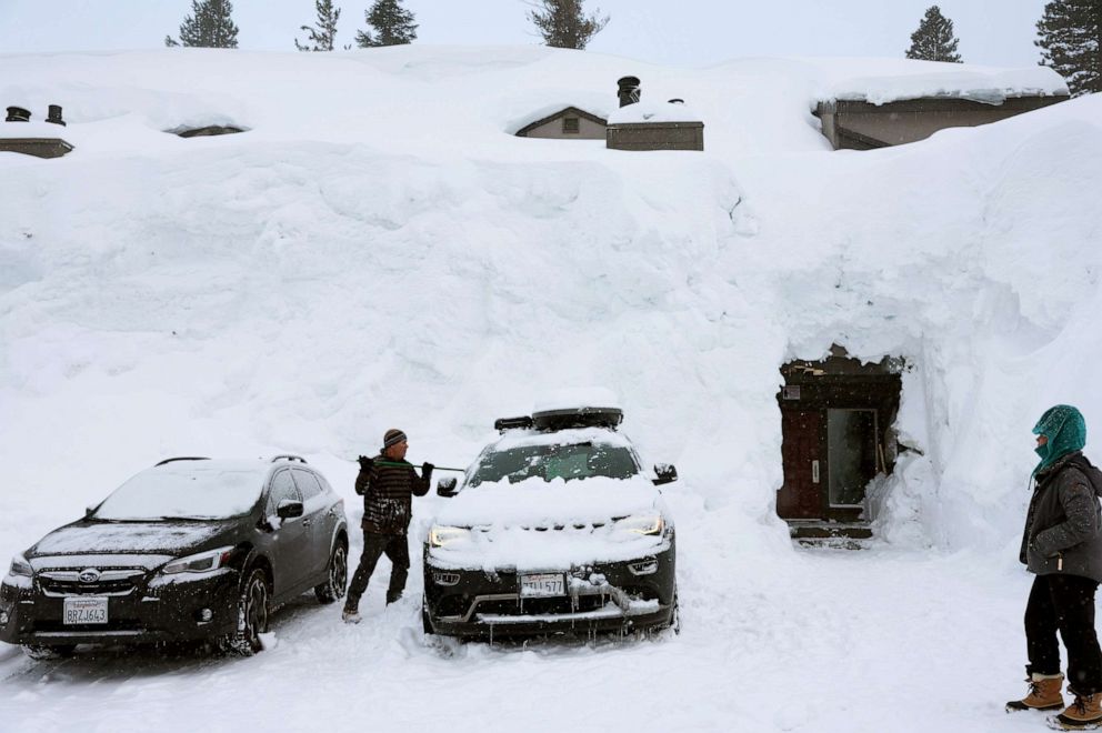 PHOTO: A person removes snow in front of lodging obscured by snowbanks piled up from new and past storms in the Sierra Nevada mountains, March 29, 2023, in Mammoth Lakes, Calif.