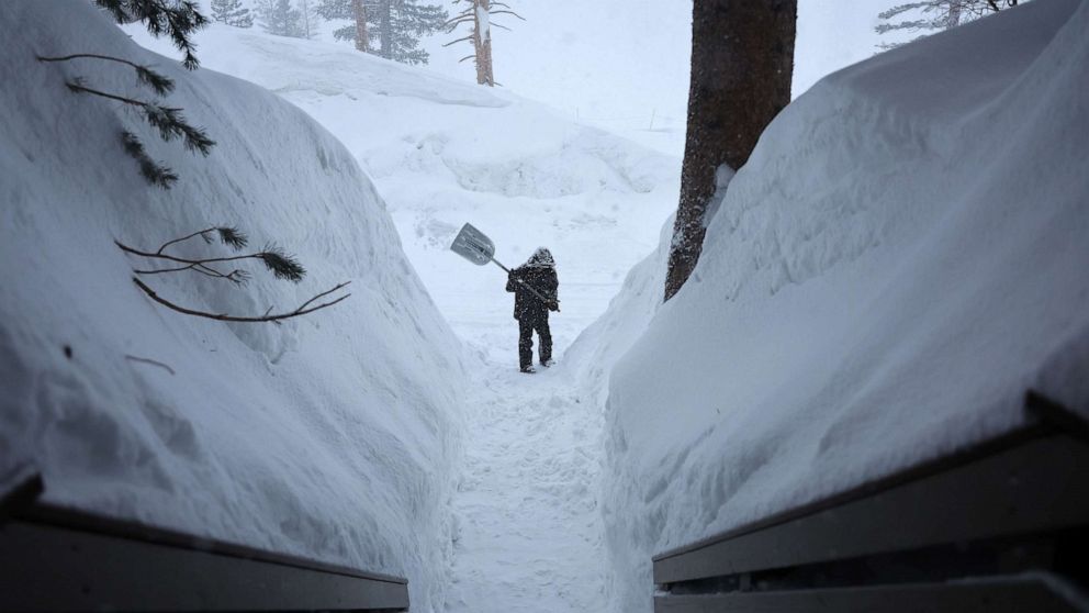 PHOTO: A worker shovels a walkway as snow falls in the Sierra Nevada mountains from yet another storm system which is bringing heavy snow to higher elevations on March 28, 2023 in Mammoth Lakes, Calif.