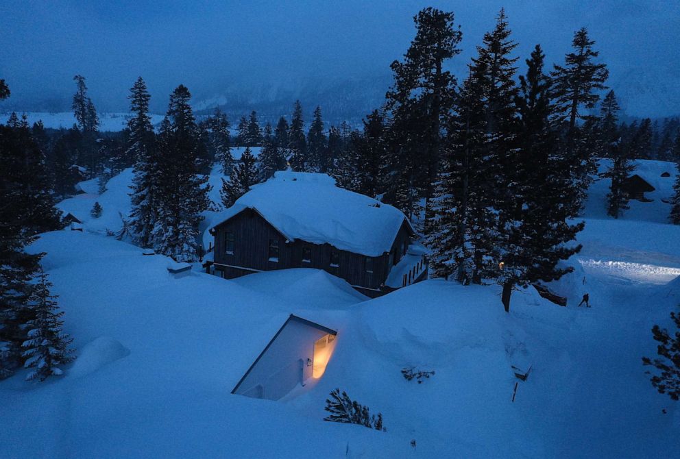 PHOTO: As night falls, a person shovels snow in the Sierra Nevada mountains, March 29, 2023 in Mammoth Lakes, Calif.