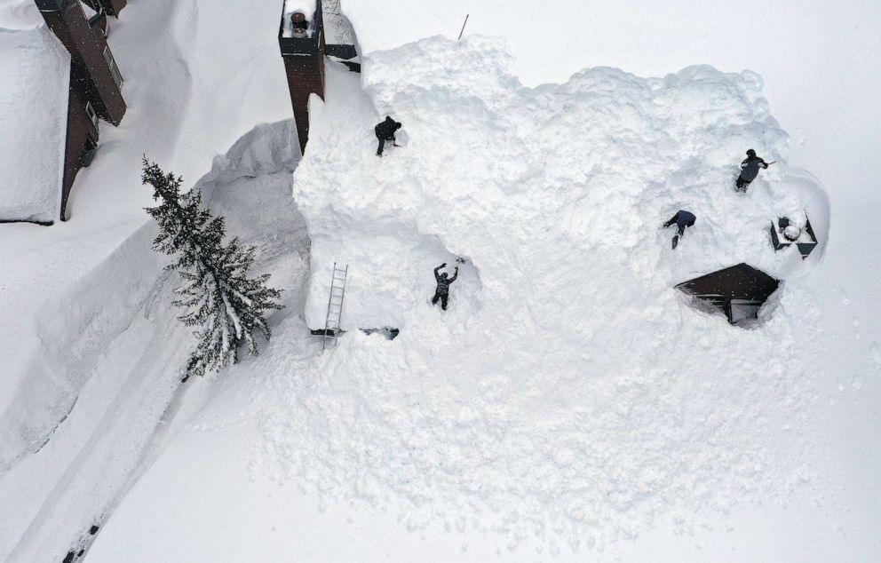 PHOTO: Workers remove snow from the roof of a condominium complex in the Sierra Nevada mountains, after yet another storm system brought heavy snowfall, March 29, 2023, in Mammoth Lakes, Calif.